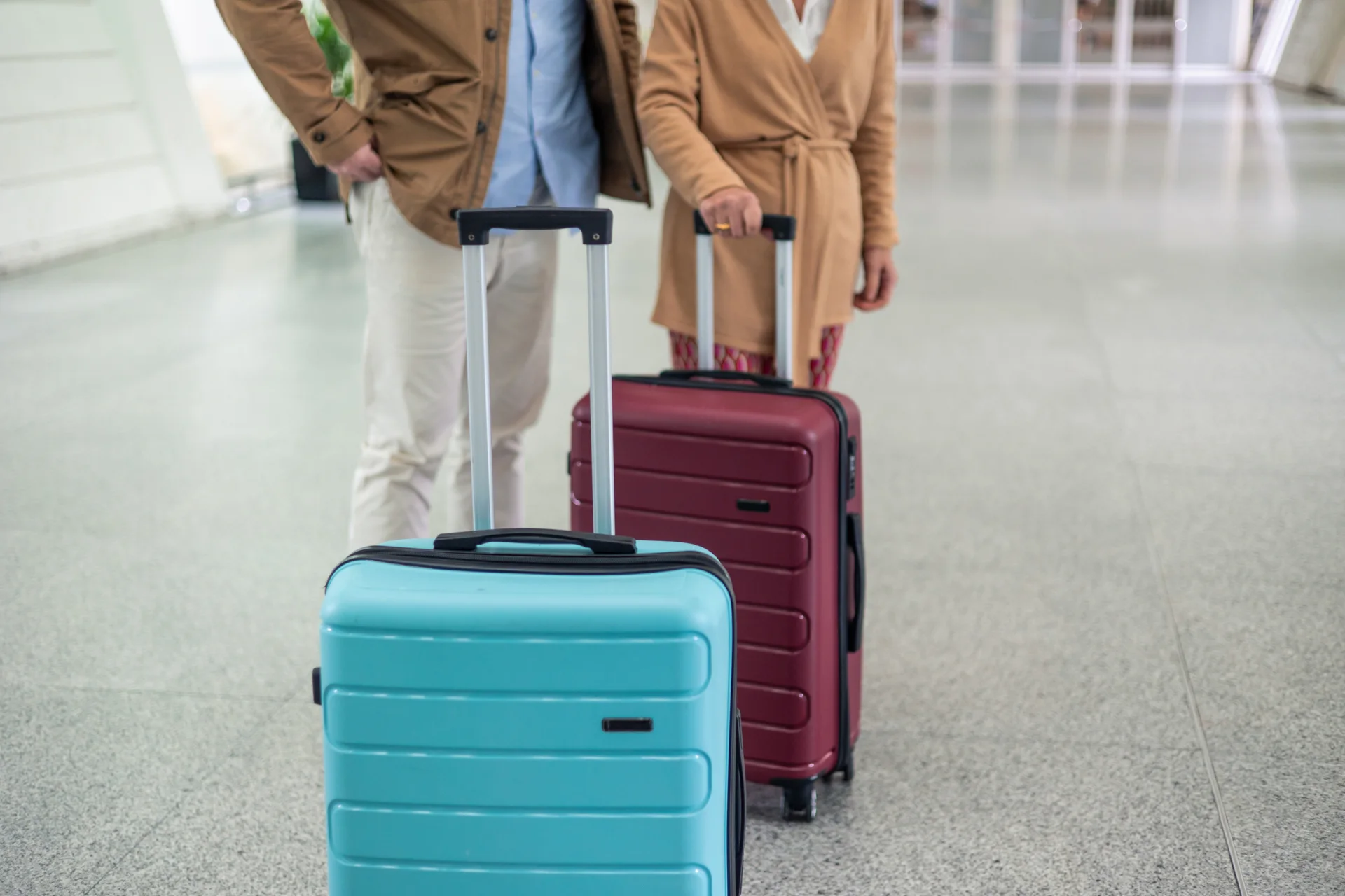 Two travellers with wheeled suitcases in an indoor concourse